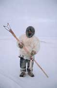 Aipilik, an Inuk hunter in fox furs with Kakivak (Inuit fish spear) & fish. Igloolik, Nunavut, Canada