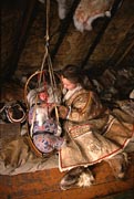 Inside a reindeer skin tent a Nenets mother comforts her baby. Yamal, Siberia, Russia